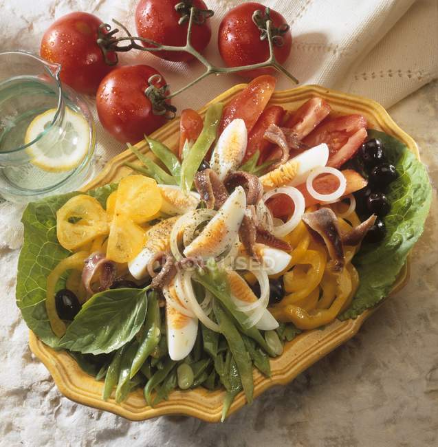 Повышенный вид на салат ниуаз с анчоусами, вареными яйцами, оливками и овощами — стоковое фото