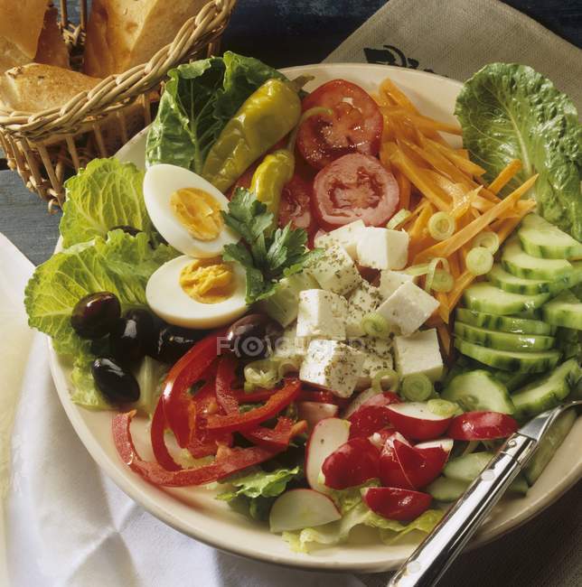 Греческий салат на белой тарелке с вилкой — стоковое фото
