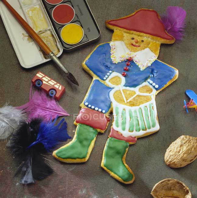 Closeup view of biscuit in the shape of a drummer with paints, colored feathers and toys — Stock Photo
