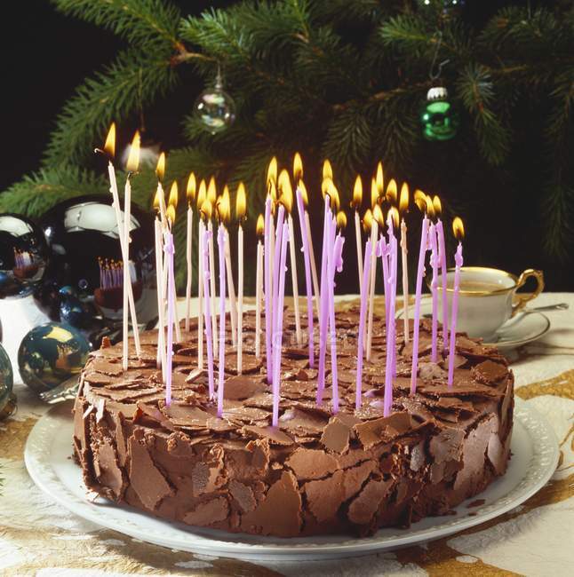 Vista de cerca de pastel de chocolate con velas encendidas - foto de stock