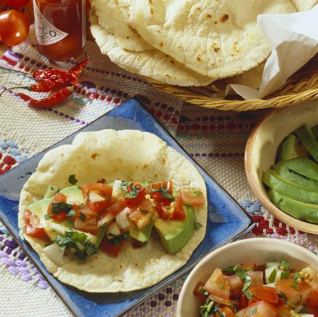 Tortilla mit Avocado und Tomatenfüllung auf blauem Teller — Stockfoto