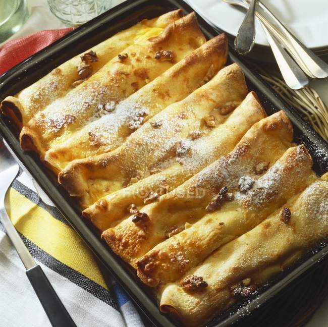 Closeup view of crepes with vanilla cream and nuts in baking dish — Stock Photo