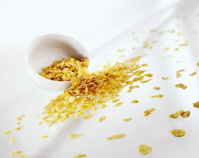 Nahaufnahme einer verschütteten Schüssel Cornflakes auf weißer Oberfläche — Stockfoto