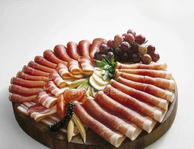 Ham platter garnished with grapes — Stock Photo