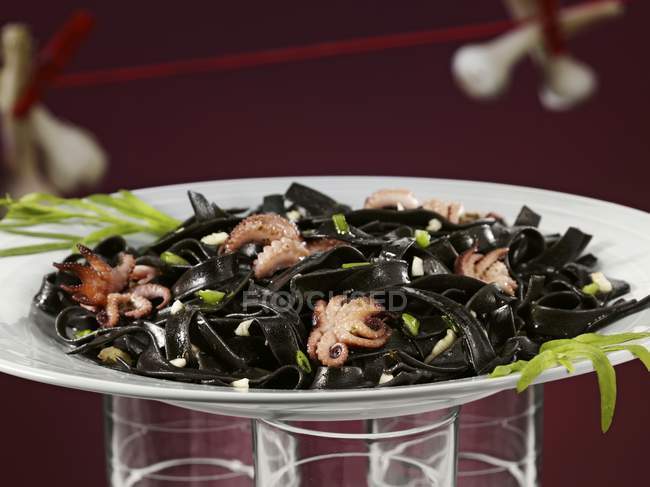 Black pasta with octopuses and seaweeds — Stock Photo