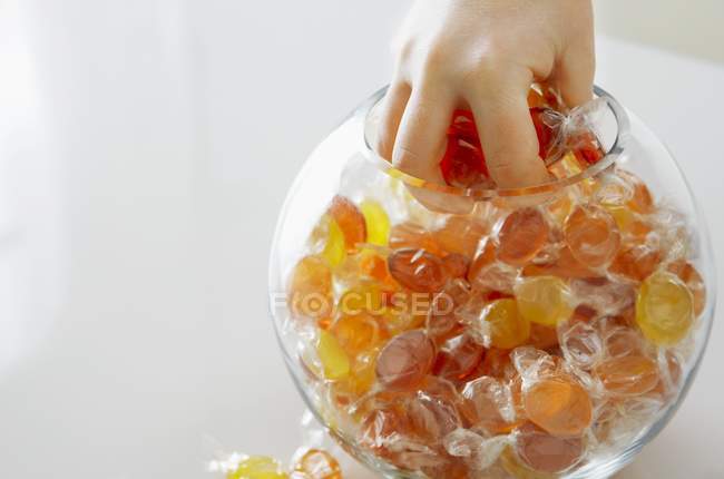 Обрізаний вид руки, що захоплює цукерки з солодкої банки — стокове фото