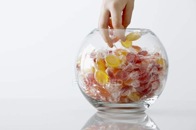 Primo piano vista ritagliata di mano prendendo caramelle da vaso di vetro — Foto stock