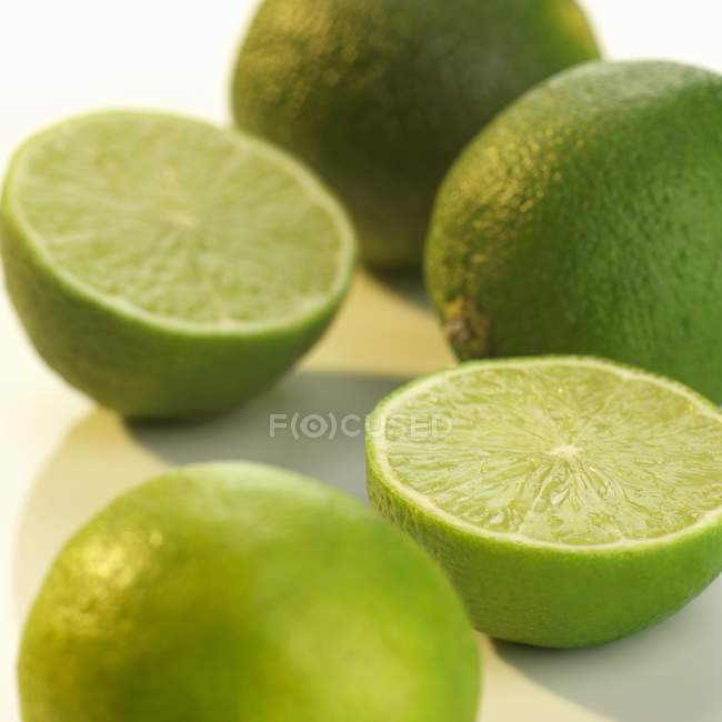 Limes entières et coupées en deux — Photo de stock