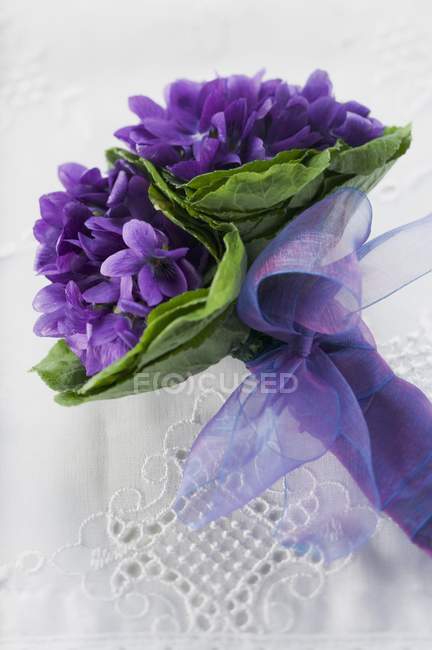 Closeup view of bunch of violets with purple bow — Stock Photo