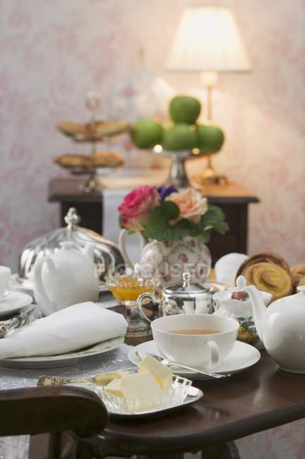 Coisas de chá e prato de manteiga na mesa colocada — Fotografia de Stock