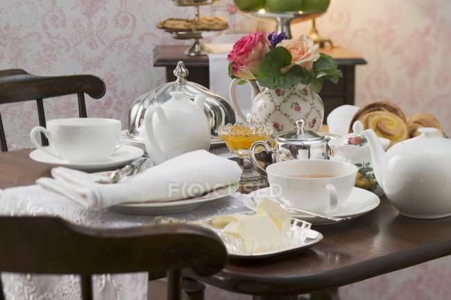 Plat de thé, pâtisserie et beurre sur table dressée — Photo de stock