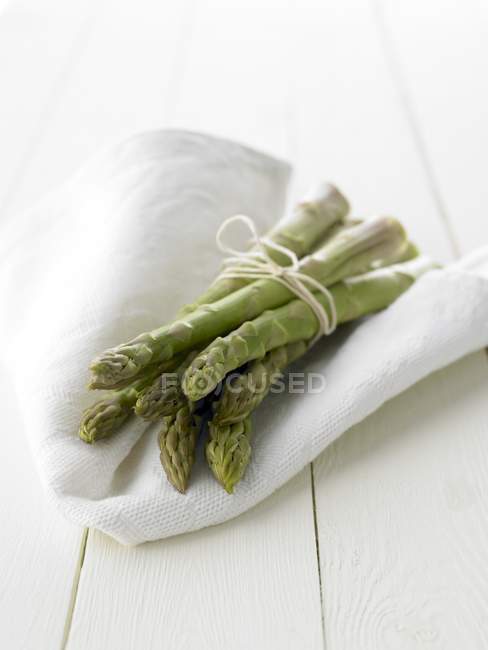 Asperges vertes sur tissu blanc — Photo de stock