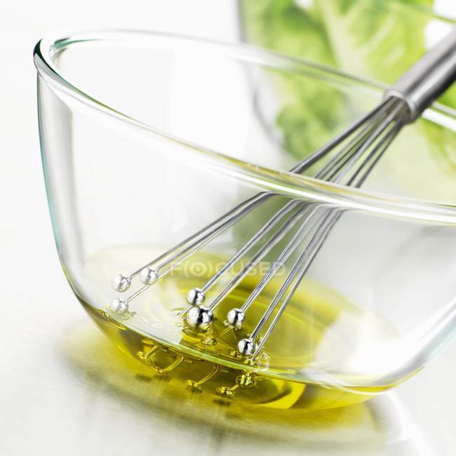 Closeup tilted view of mixing salad dressing with whisk — Stock Photo