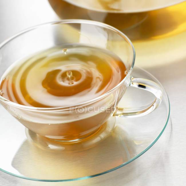 Drop of tea falling into a cup — Stock Photo