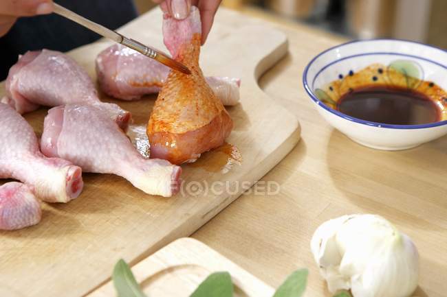 Koch bürstet Hühnerschenkel mit Marinade — Stockfoto