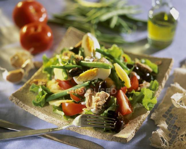 Salade nioise on wooden plate with fork — Stock Photo