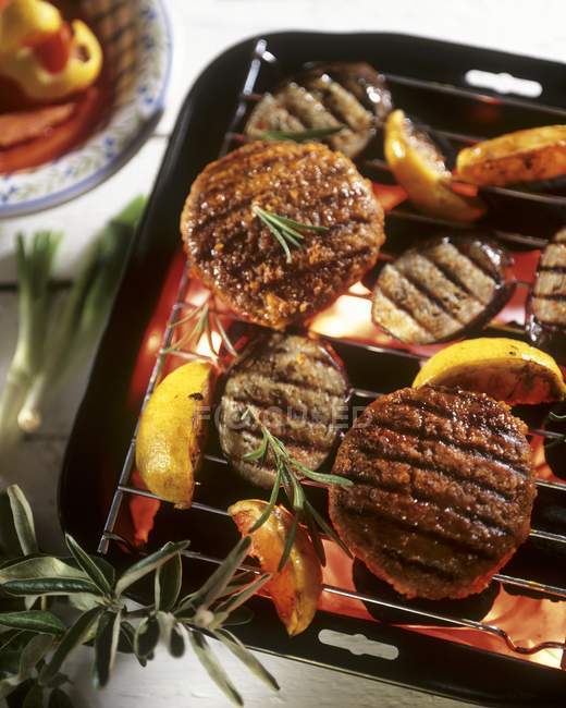 Grilled burgers, aubergines and lemons on black tray — Stock Photo