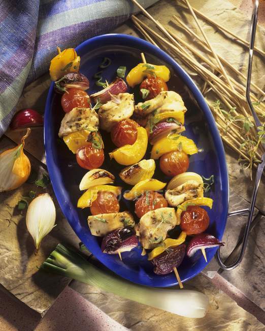 Grilled poultry and vegetable kebabs on purple dish — Stock Photo
