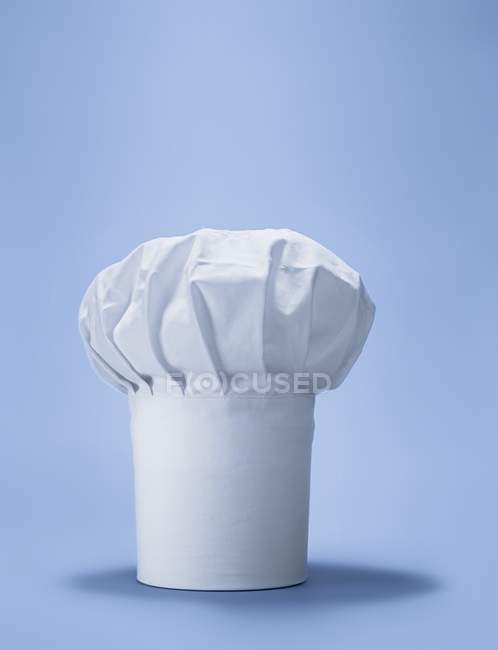 Вид крупным планом одной шляпы шеф-повара на голубой поверхности — стоковое фото