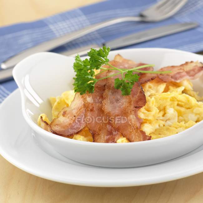 Scrambled egg with bacon and herb in white dish — Stock Photo