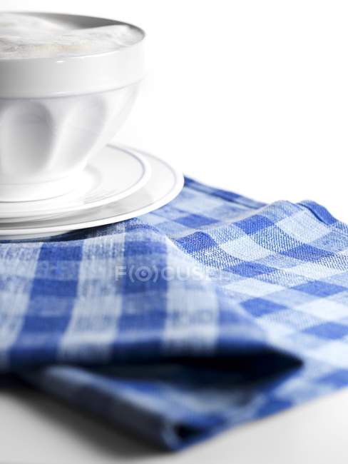 Closeup view of Caf au lait in bowl on checkered cloth — Stock Photo