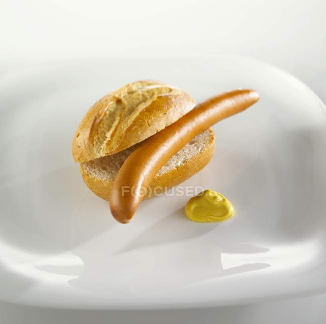Vista de cerca de una salchicha Bockwurst en un panecillo con mostaza - foto de stock