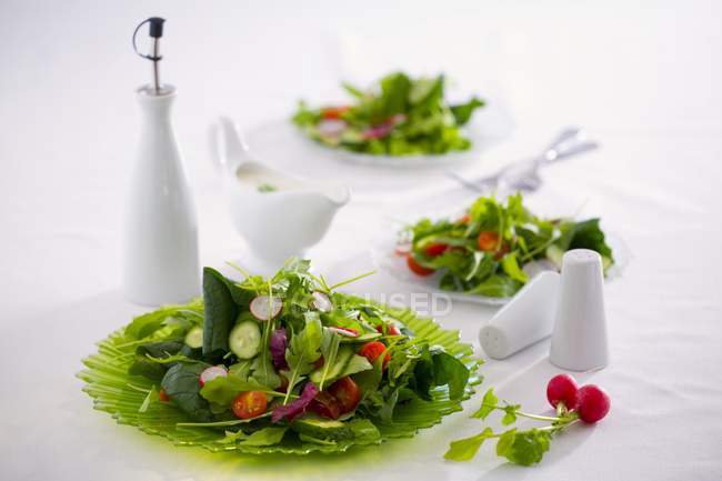 Spring salad with cucumber, radishes and cherry tomatoes on white surface — Stock Photo