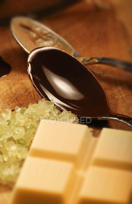 Weiße Kuvertüre, kandierte Zitronenschale und dunkle Kuvertüre im Löffel — Stockfoto