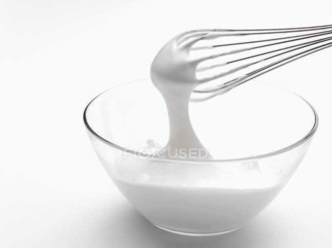 Closeup view of whipped white cream in bowl with whisk — Stock Photo