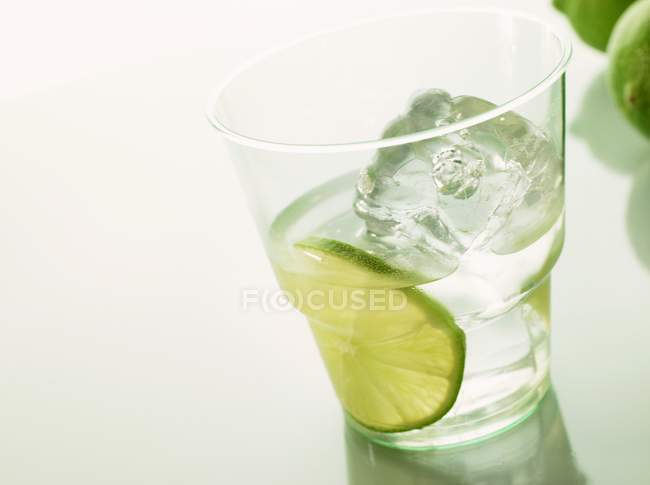 Closeup view of mineral water with slice of lime and ice cube — Stock Photo