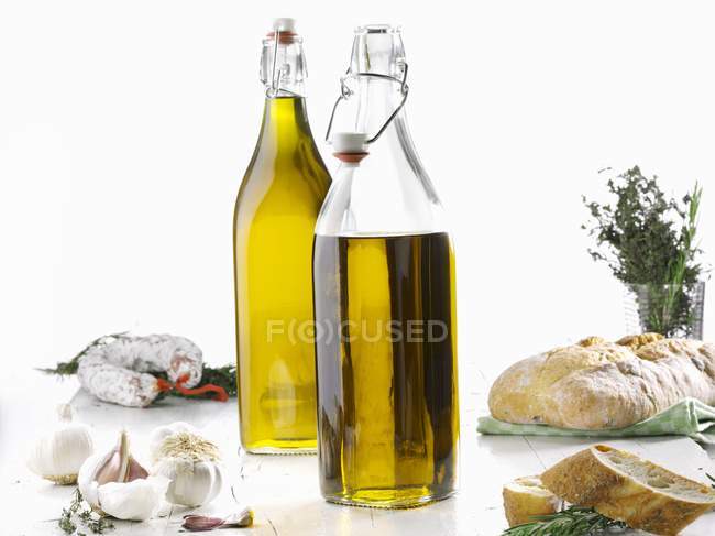 Olivenöl, Knoblauch, Salami, Kräuter und Ciabatta auf weißer Oberfläche — Stockfoto