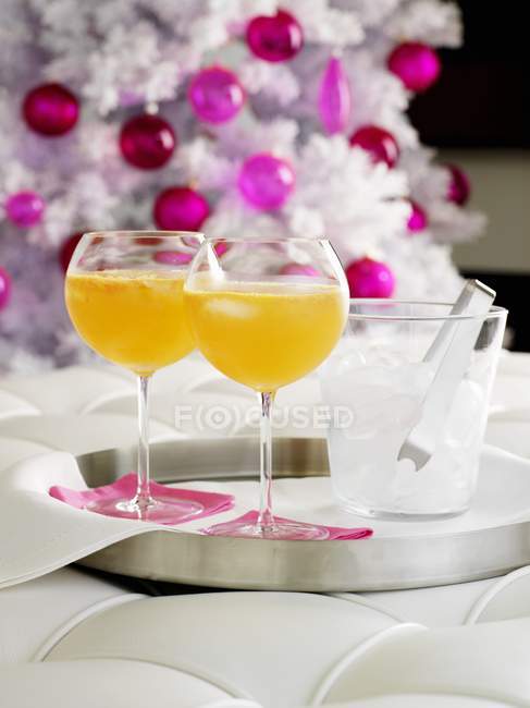 Orangengetränke mit Eiswürfeln und Weihnachtsbaum auf Hintergrund — Stockfoto