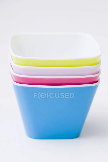 Vista de primer plano de platos apilados de colores en la superficie blanca - foto de stock