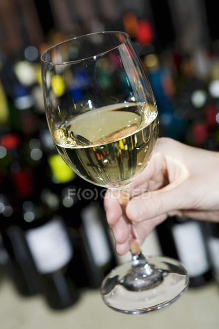 Hand holding glass of white wine — Stock Photo