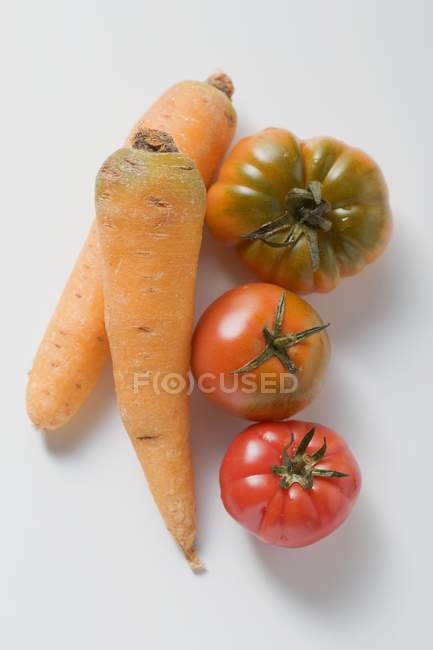 Two carrots and three tomatoes — Stock Photo