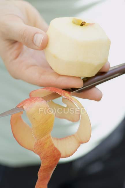 Manos femeninas pelar manzana - foto de stock