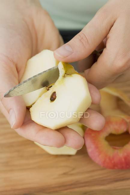 Frauenhände schneiden Apfel in Viertel — Stockfoto