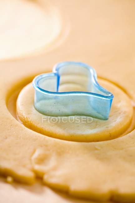 Closeup view of cutting heart shape cookie from dough — Stock Photo