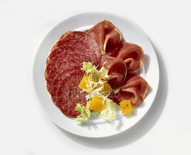 Salami mit rohem Schinken auf Teller — Stockfoto