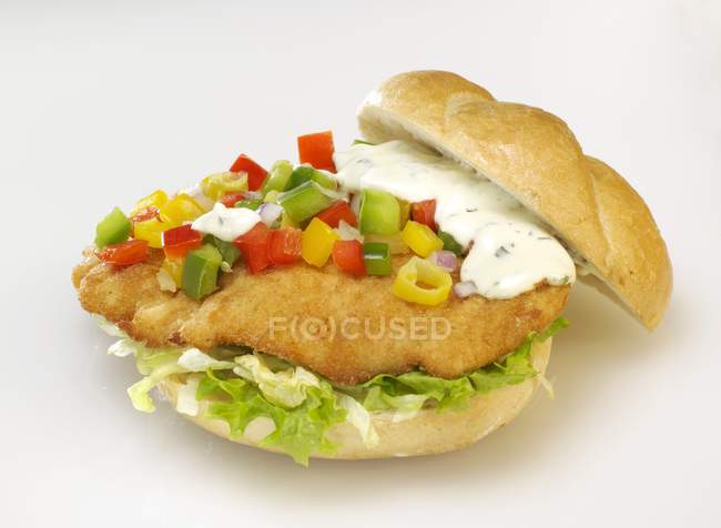 Closeup view of escalope with salad, diced peppers and remoulade in bread roll — Stock Photo