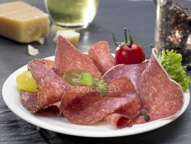 Slices of salami on plate — Stock Photo