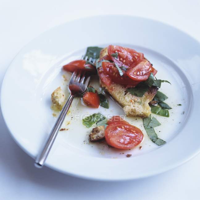 Брушетта - помідори на підсмаженому хлібі на білій тарілці з виделкою — стокове фото