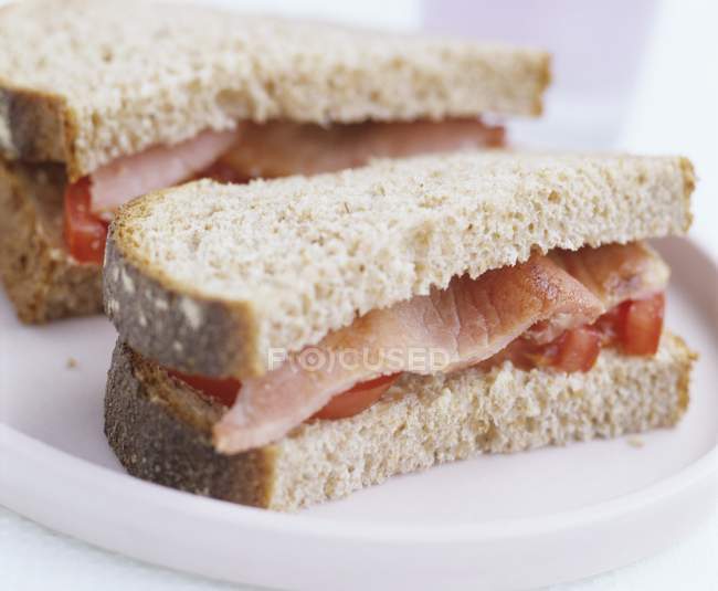 Speck- und Tomatensandwiches auf weißem Teller — Stockfoto