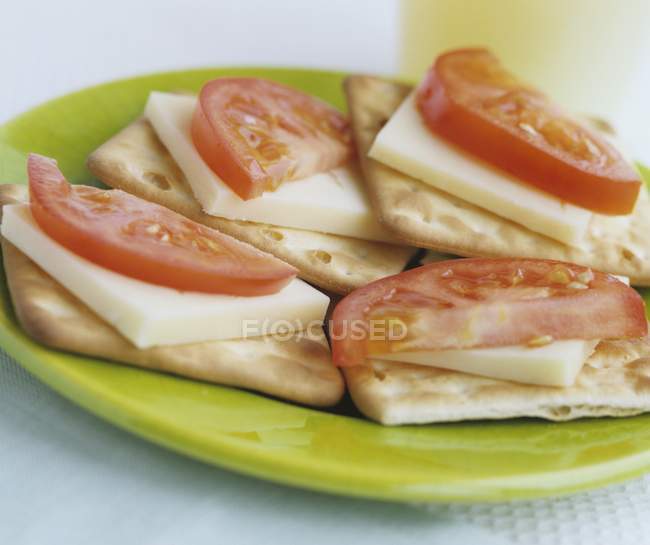 Cheese and tomato on crackers — Stock Photo