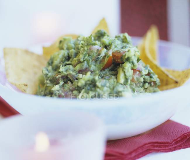 Guacamole mit Tortilla-Chips auf weißem Teller über rotem Handtuch — Stockfoto