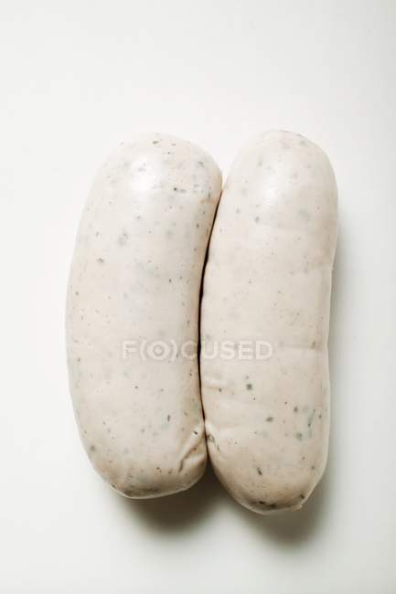 Closeup top view of two Weisswurst sausages on white surface — Stock Photo