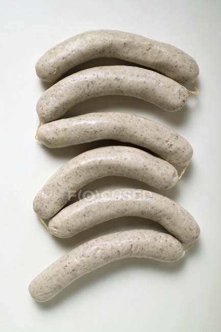 Six fresh Weisswurst sausages on white surface — Stock Photo
