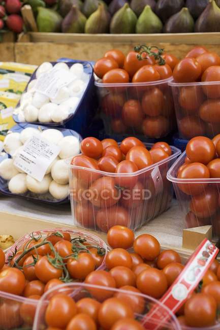 Tomatoes and mushrooms in plastic punnets — Stock Photo