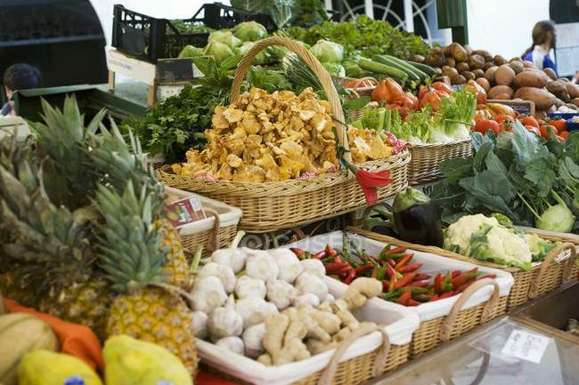 Puesto de mercado con frutas, verduras, setas y hierbas en cestas - foto de stock