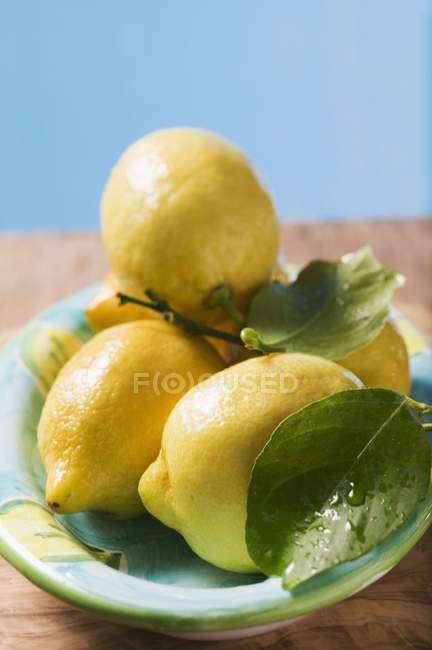 Lemons with leaves on plate — Stock Photo